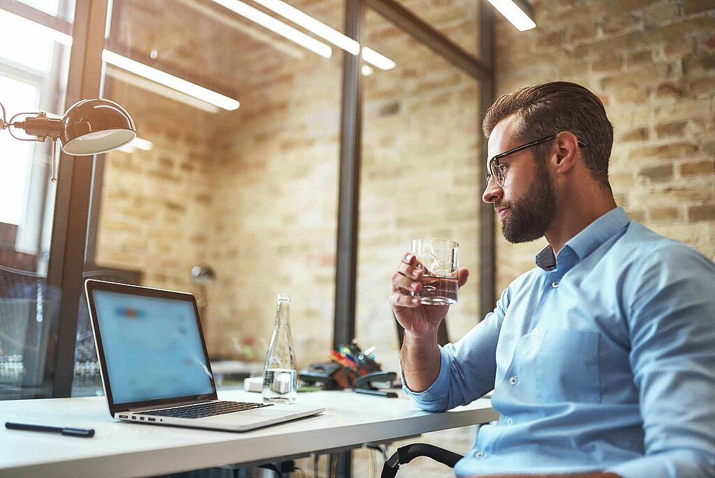 Kleines Unternehmen mit einem arbeitenden Mitarbeiter welcher Wasser trink