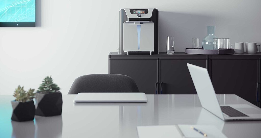 Arbeitsplatz mit einem Waterlogic Wasserspender als Tischgerät auf einem Sideboard  