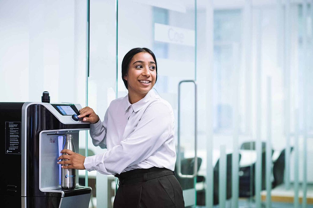 Mitarbeiterin füllt Ihre Glas mit Wasser aus einem Waterlogic Wasserspender