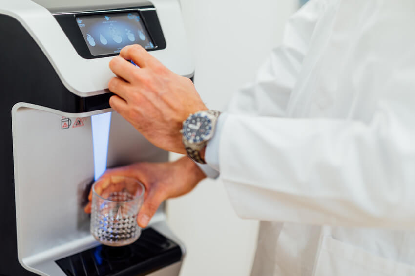 Person füllt sich ein Glas mit Wasser an einem Waterlogic Wasserspender 