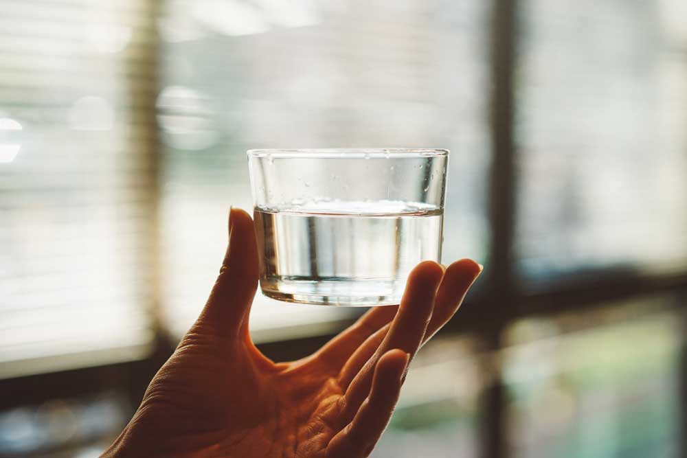 Volles Wasserglas in einer Hand 